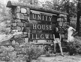 A man and a woman stand next to a sign for the ILGWU Unity House